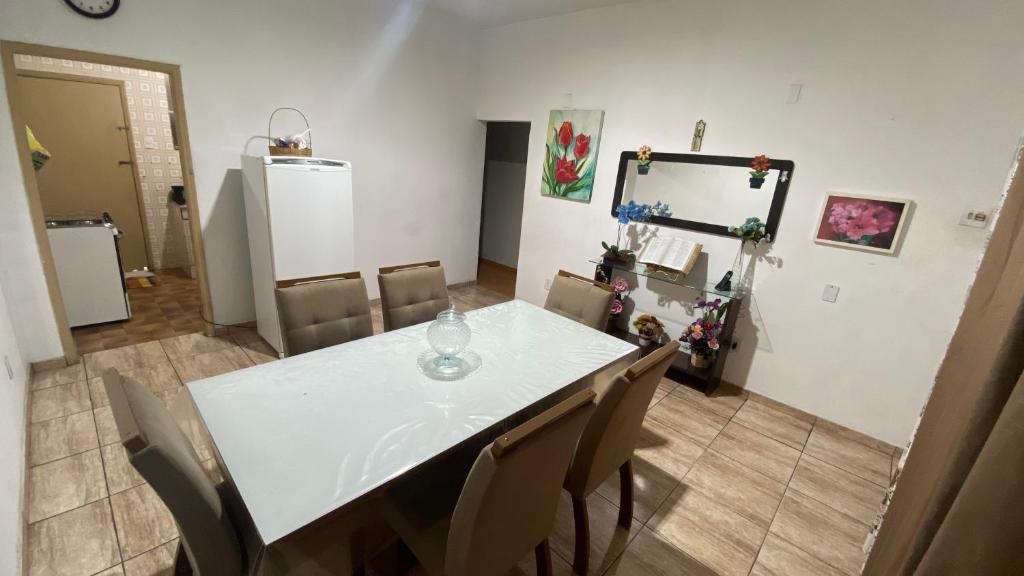 a dining room with a white table and chairs at Quarto Aconchegante in Cruzeiro