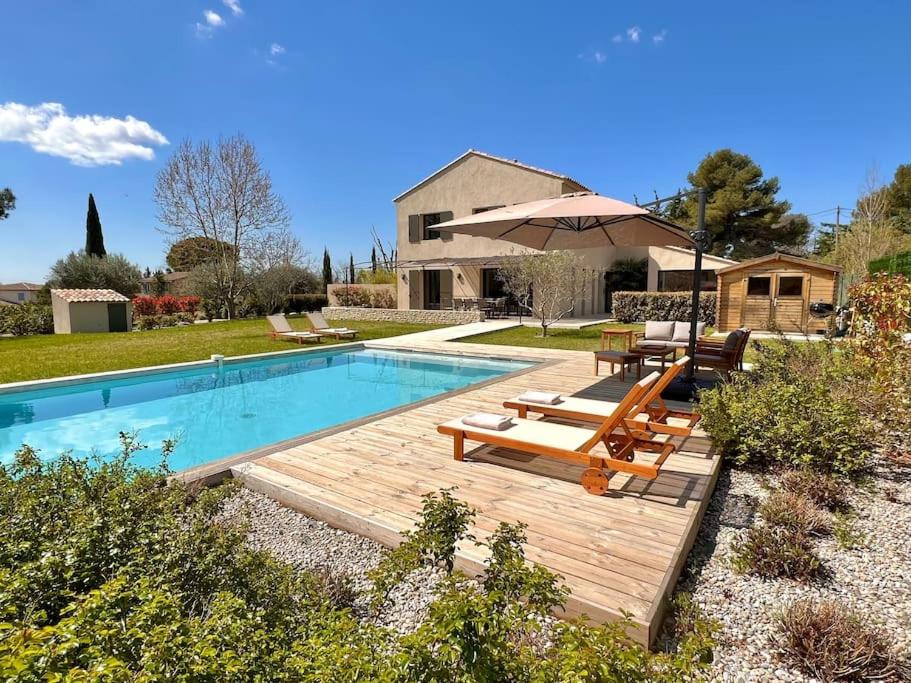 une piscine avec une terrasse en bois et un parasol dans l'établissement Villa moderne et chaleureuse au milieu vignes et calme absolu à Aix en Provence, à Aix-en-Provence