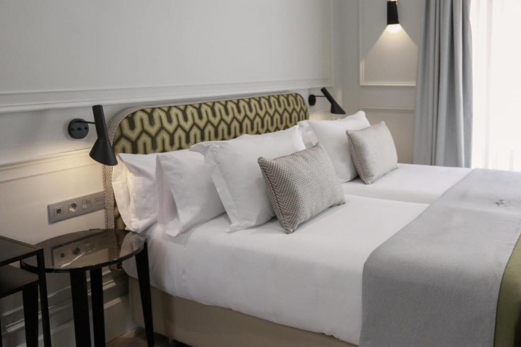 a bedroom with a white bed with pillows at Hotel Boutique Casa Romana Villa in Seville