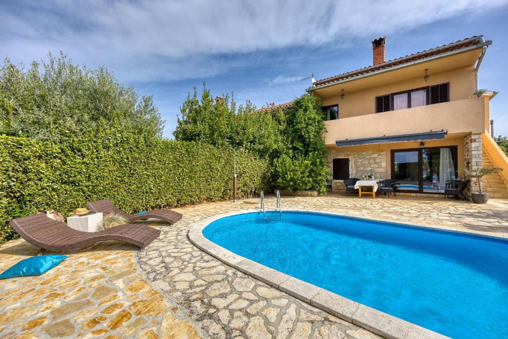 a villa with a swimming pool in front of a house at Holiday house Marinela with Private Pool and Fenced Garden in Radetići