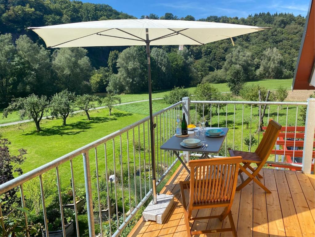 a table and chairs on a deck with an umbrella at Kleine-Radoase Ferienwohnung mit Super- Aussicht in Weilburg