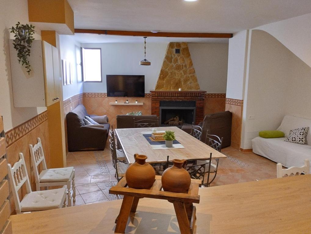 La Casa de la Buhardilla في Fondón: غرفة معيشة مع طاولة ومدفأة