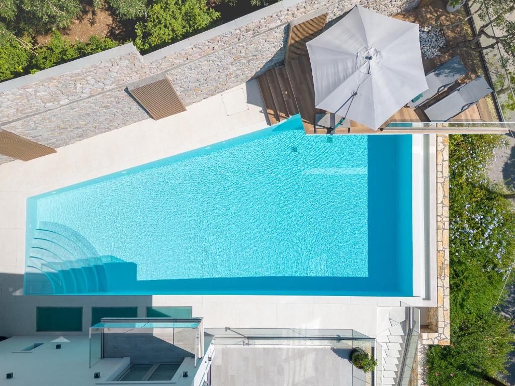 an overhead view of a swimming pool with a white umbrella at Driftwood Luxury Suite in Corfu Town