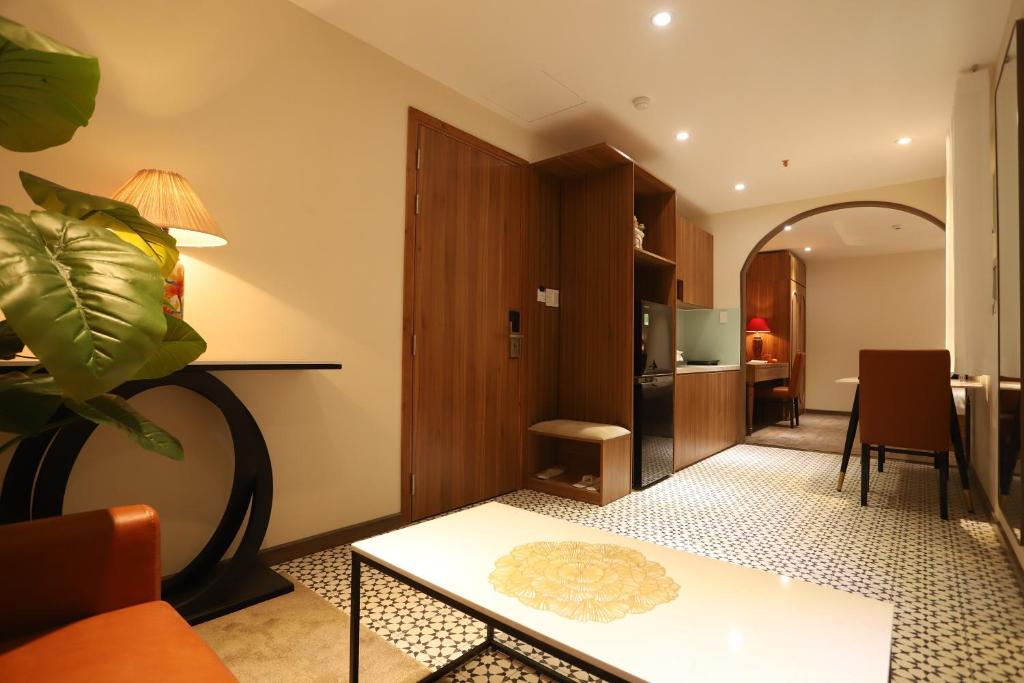 ein Wohnzimmer mit einem Tisch und einer Küche in der Unterkunft Lanura Apartments and Hotel in Ho-Chi-Minh-Stadt