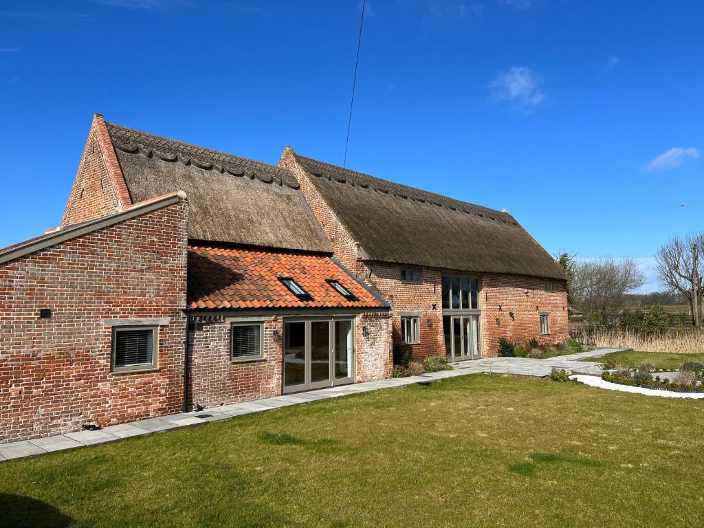 a large brick building with a grass yard in front of it at Grange Farm Barn, Filby in Filby