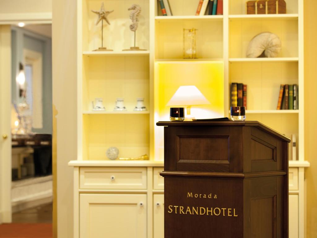 a room with a book shelf with a lamp in it at Morada Strandhotel Ostseebad Kühlungsborn in Kühlungsborn