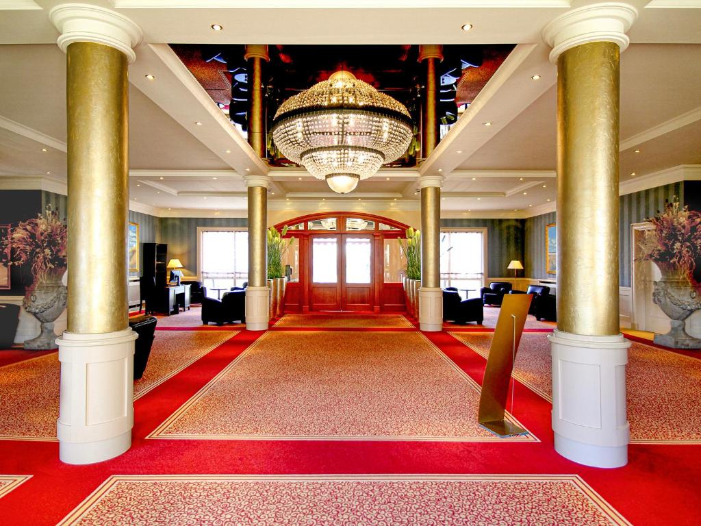 a large lobby with a chandelier and red carpet at Morada Strandhotel Ostseebad Kühlungsborn in Kühlungsborn