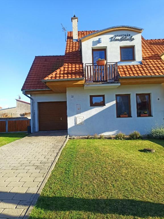 a white house with a balcony and a yard at Apartmán Vendelínka in Valtice