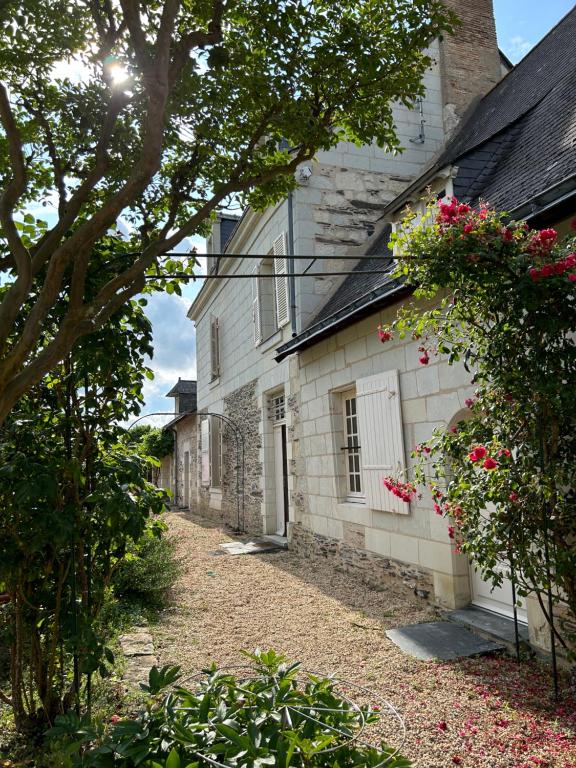 une ancienne maison en pierre avec des fleurs sur son côté dans l'établissement La Maillardière - Maison de campagne avec piscine, à Corné