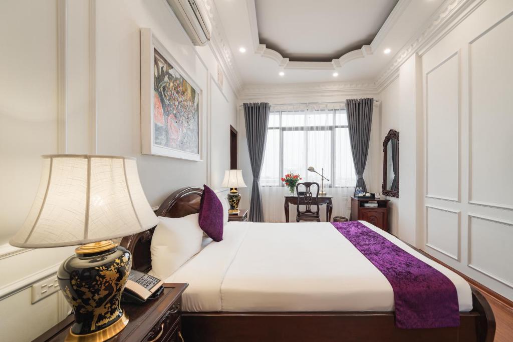 a bedroom with a bed and a lamp on a desk at Hanoi Little Town Hotel in Hanoi