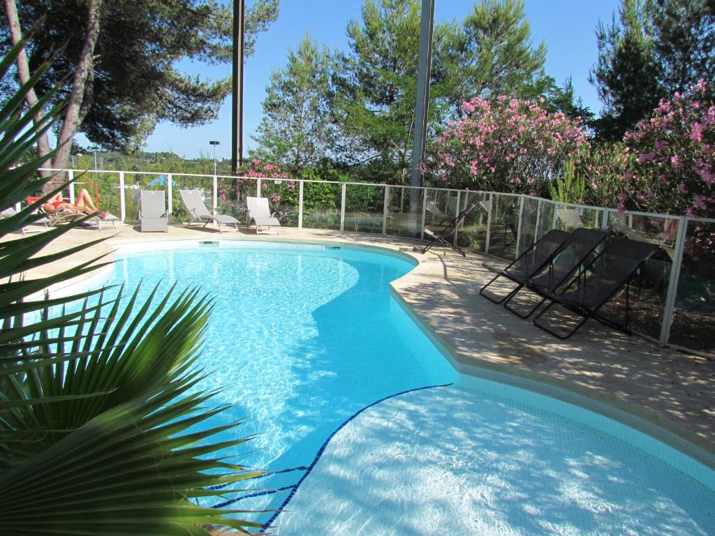 - une piscine avec 2 chaises et une clôture dans l'établissement Kyriad Montpellier Nord Parc Euromédecine, à Saint-Clément-de-Rivière