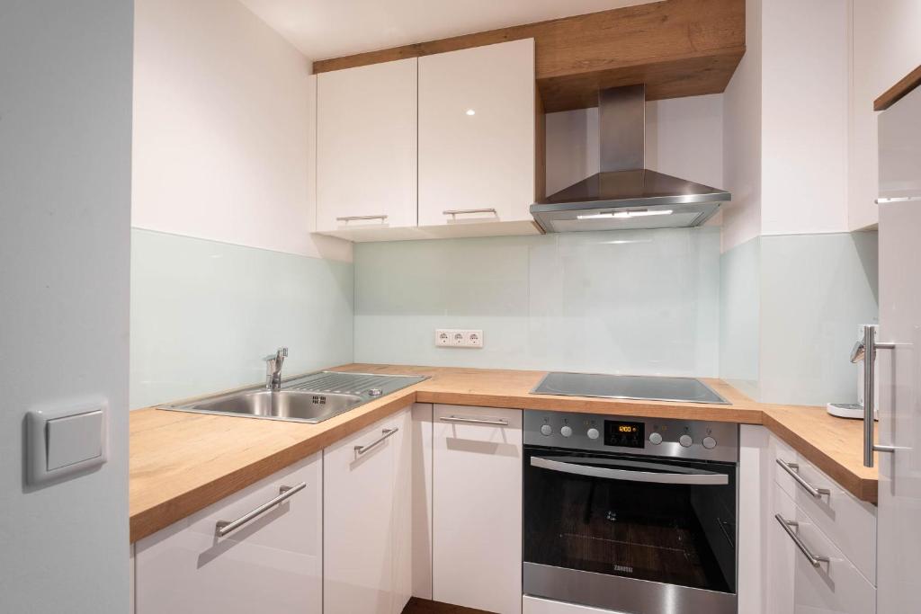 a kitchen with white cabinets and a sink and a stove at Ferienhaus zur Hackenschmiede in Mauterndorf