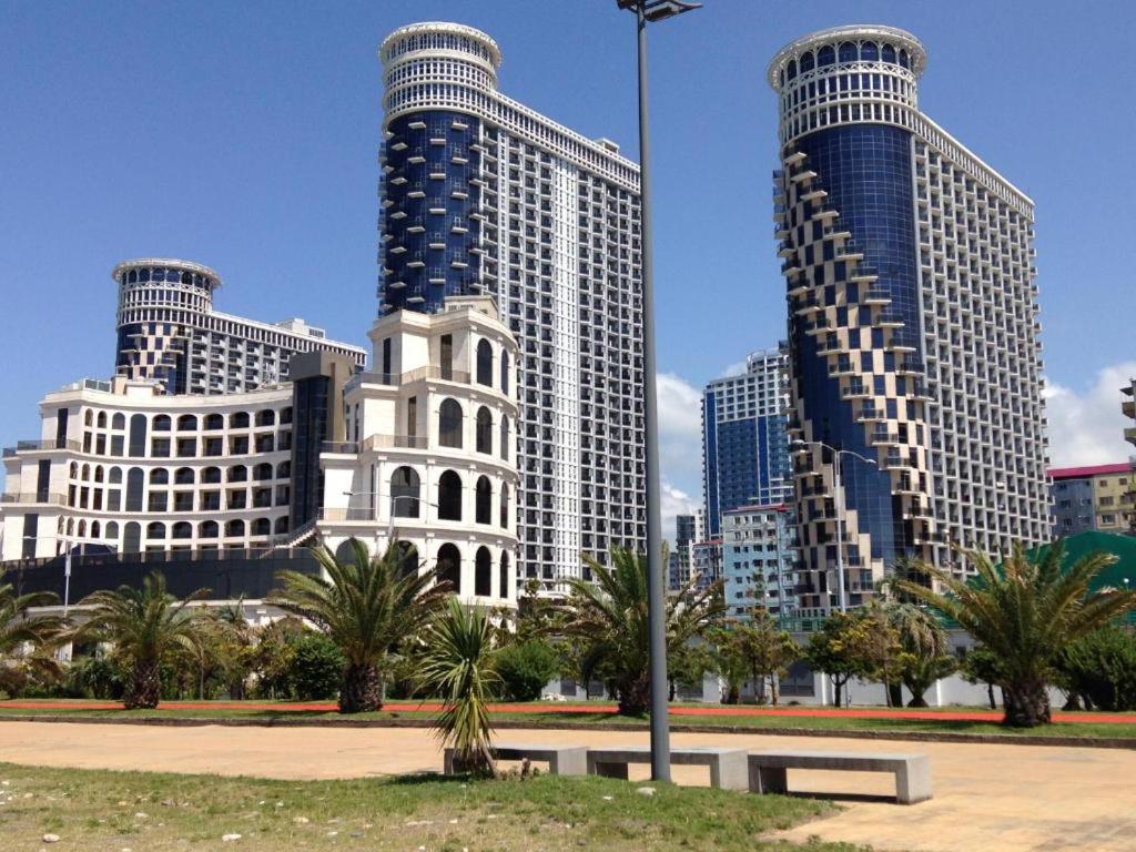 a city with tall buildings and a park with a bench at Orbi Royal Apartments in Batumi