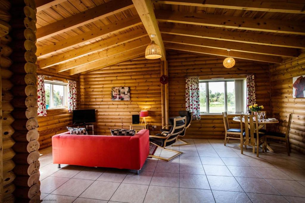 una sala de estar con un sofá rojo en una cabaña de madera en Kingfisher Lodge en Selby