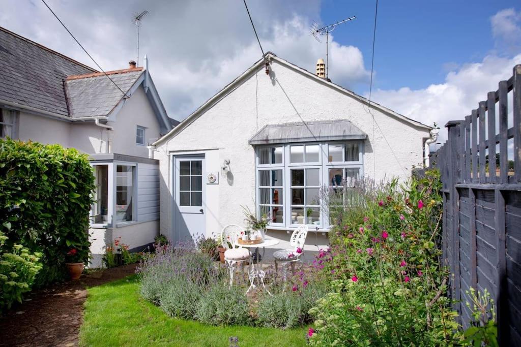 une maison blanche avec une table et des chaises dans la cour dans l'établissement Orchard Cottage, à Sidmouth