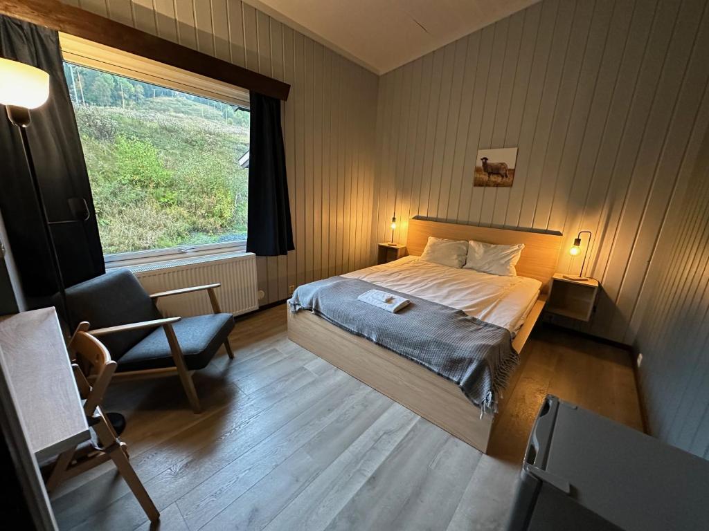 a bedroom with a bed and a chair and a window at Morgedal Gjestehus in Morgedal