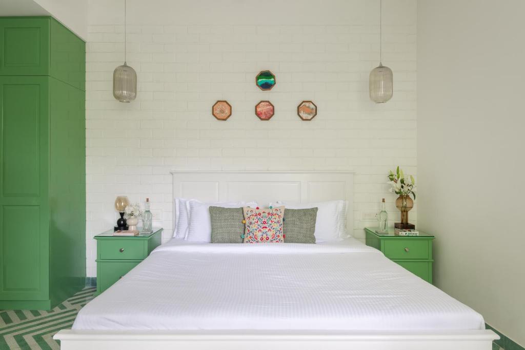 a bedroom with a large white bed with green cabinets at El Rocio Estate in Assagao