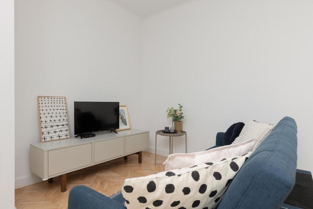 een woonkamer met een blauwe bank en een tv bij Spacious & Comfortable Studio Apartament Rajska with Balcony by Renters in Łódź