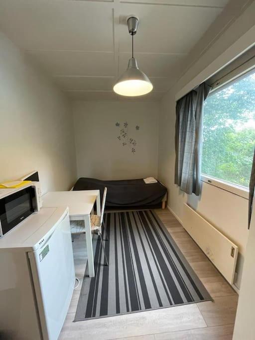 ein kleines Zimmer mit einem Bett, einem Tisch und einem Fenster in der Unterkunft Kotimaailma: Hostel Kivikkotie (room 4) in Vantaa