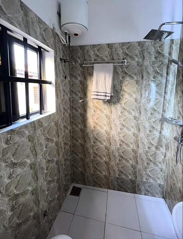 łazienka z prysznicem, toaletą i oknem w obiekcie Cosy Spiral w mieście Lomé