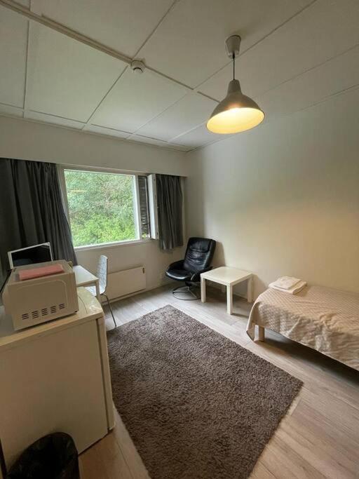 ein Schlafzimmer mit einem Bett, einem Stuhl und einem Fenster in der Unterkunft Kotimaailma, Hostel Kivikkotie (room 6) in Vantaa