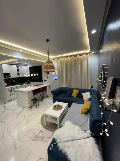ein Wohnzimmer mit einem blauen Sofa und einer Küche in der Unterkunft Appartement Elégant in Casablanca
