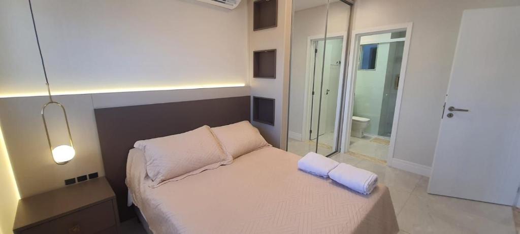 a small bedroom with a bed with two pillows at Apartamento 2 suítes 200m da praia de Bombas in Bombas