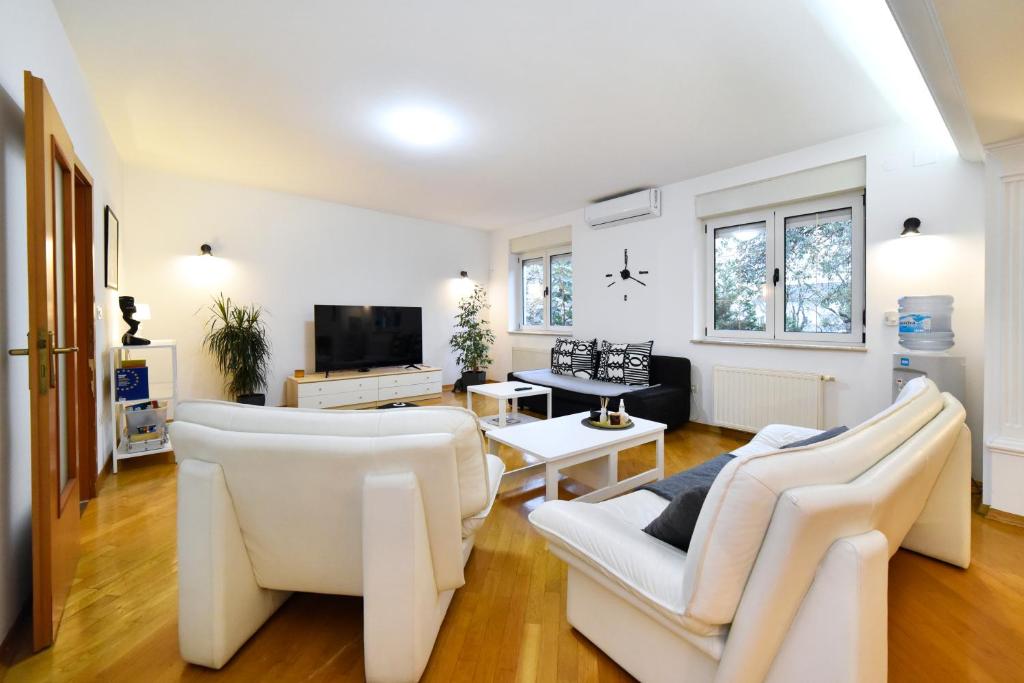 a living room with white furniture and a tv at GreenHouse in Zagreb