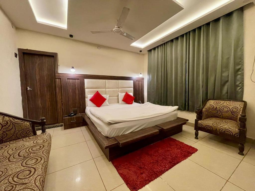 Un dormitorio con una cama con almohadas rojas y una silla en Hotel Himgiri, en Jammu