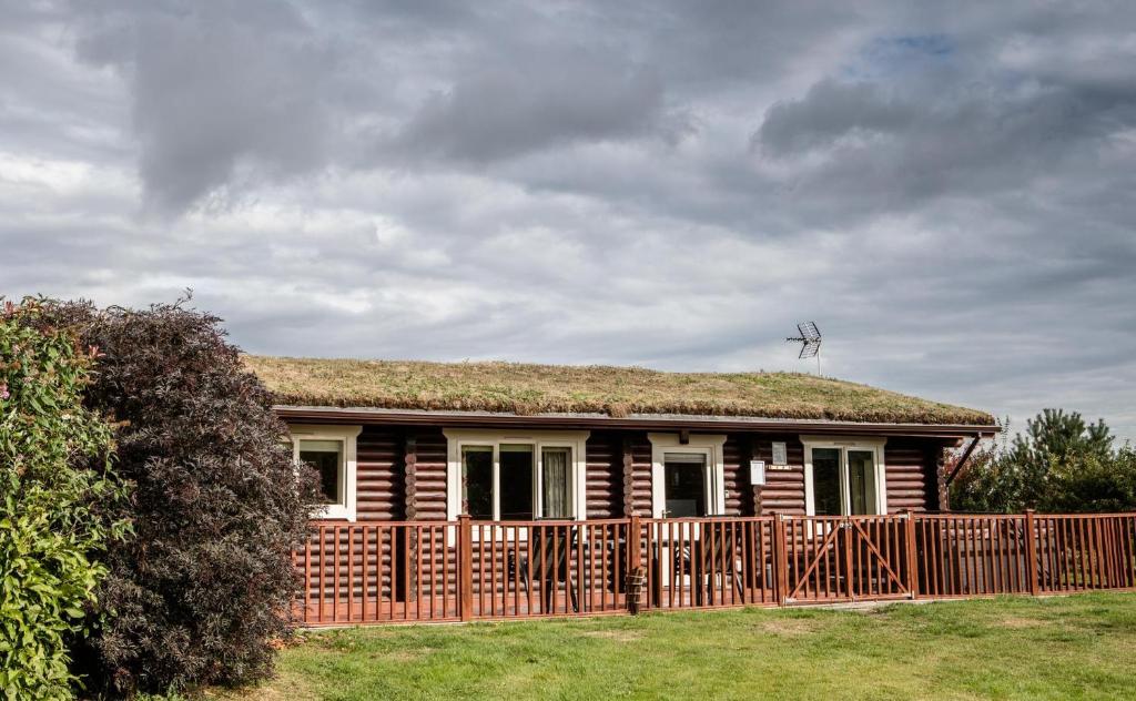 a house with a grass roof with a wooden fence at Mallard Lodge in Selby