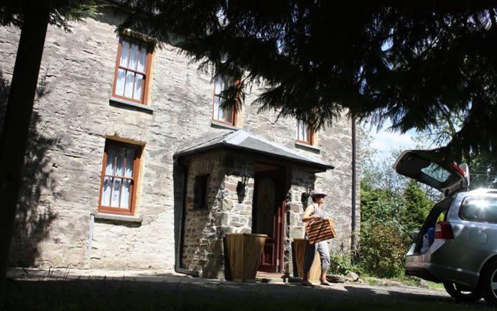 a woman standing outside of a stone house at Old Stone Cottage in Llandysul