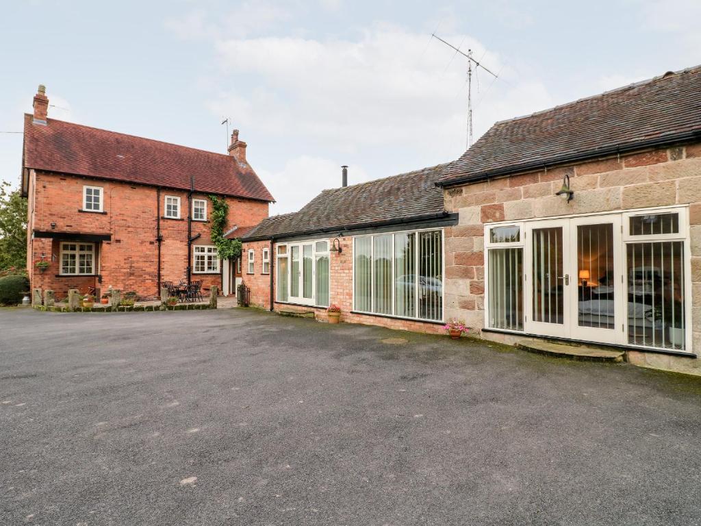 een lege parkeerplaats voor twee bakstenen gebouwen bij Abbey View Farm Cottage in Uttoxeter