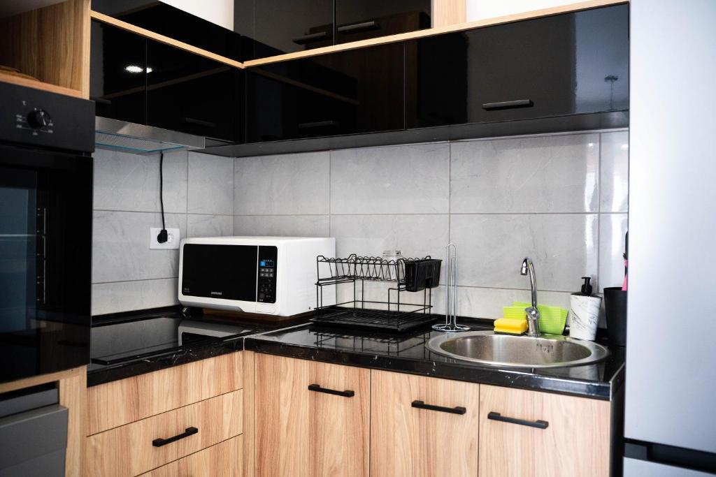a kitchen with a sink and a microwave at Apartman Arija in Ruma