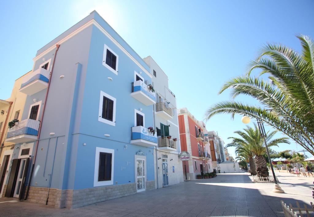 un edificio azul y blanco en una calle con palmeras en Le Nereidi BeB, en Margherita di Savoia