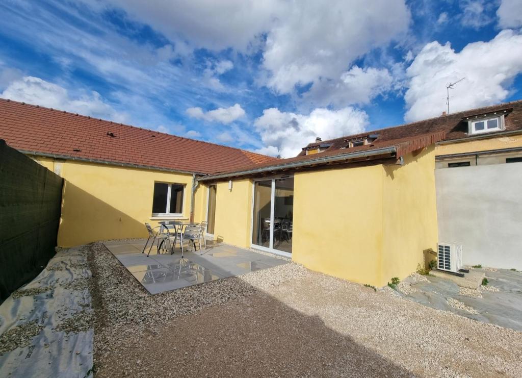 une maison jaune avec des chaises sur une terrasse dans l'établissement Maison 700m du centre-ville, à Auxerre