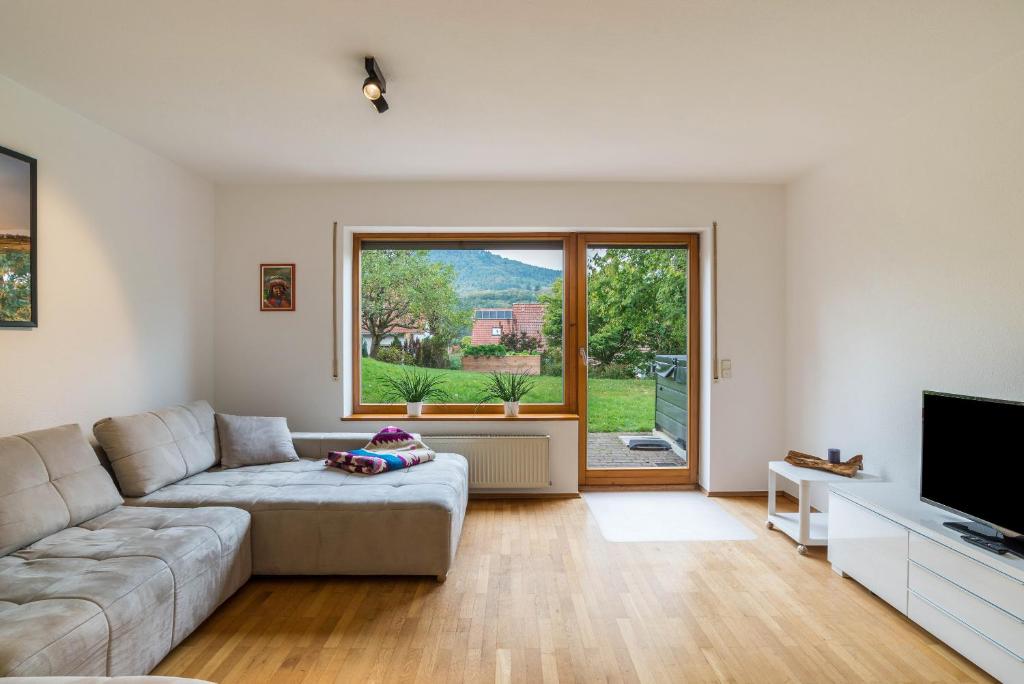 a living room with a couch and a large window at Haus Gartenblick in Annweiler am Trifels