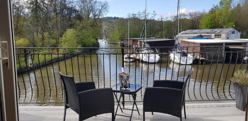 a balcony with a table and chairs and boats in the water at Marina Boathouse, lake windermere lets in Bowness-on-Windermere