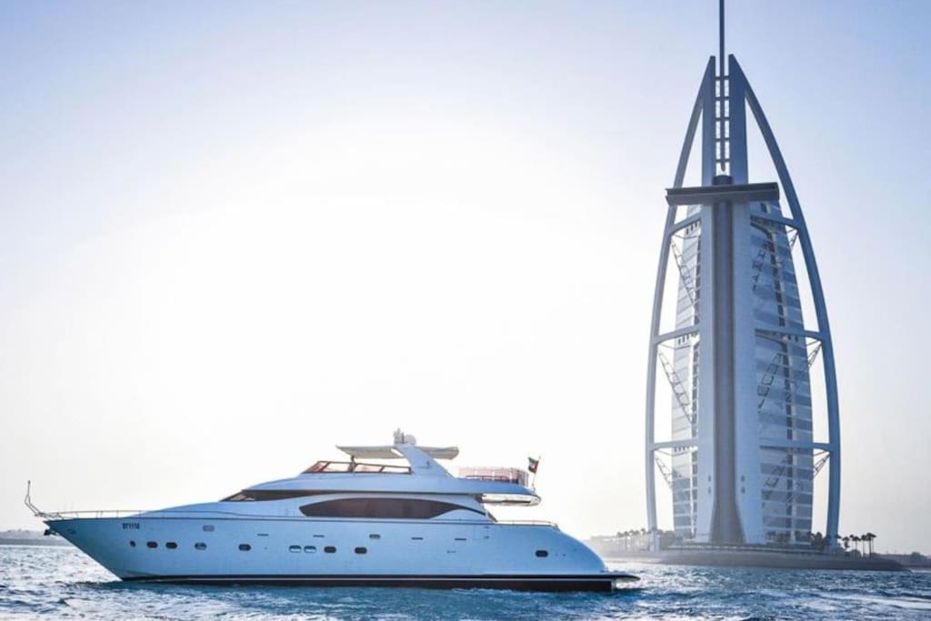 a yacht in the water next to a building at OFFER-Book 4BR Villa and Ride at Luxury Yacht FREE in Dubai