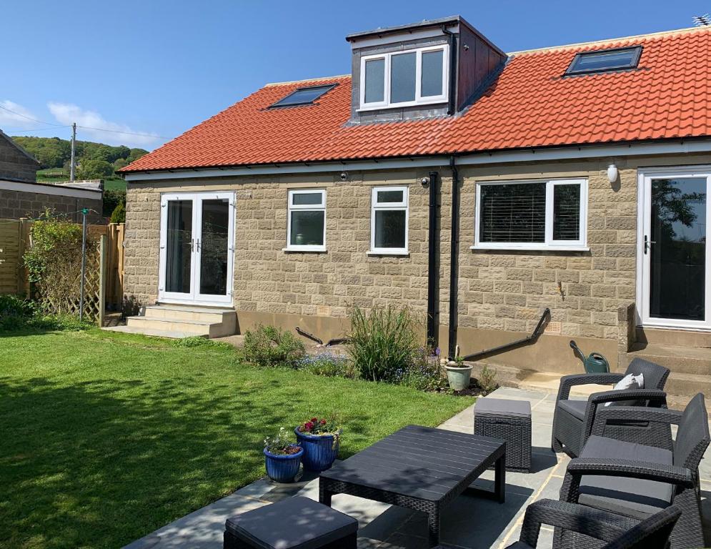 a patio with chairs and tables and a house at Sea Fern Luxury Cottage Fylingthorpe in Fylingthorpe