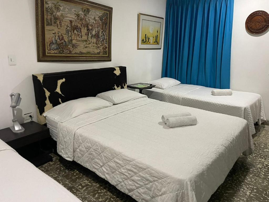 two beds in a room with blue curtains at Hotel Fegali Art Boutique in Cartagena de Indias