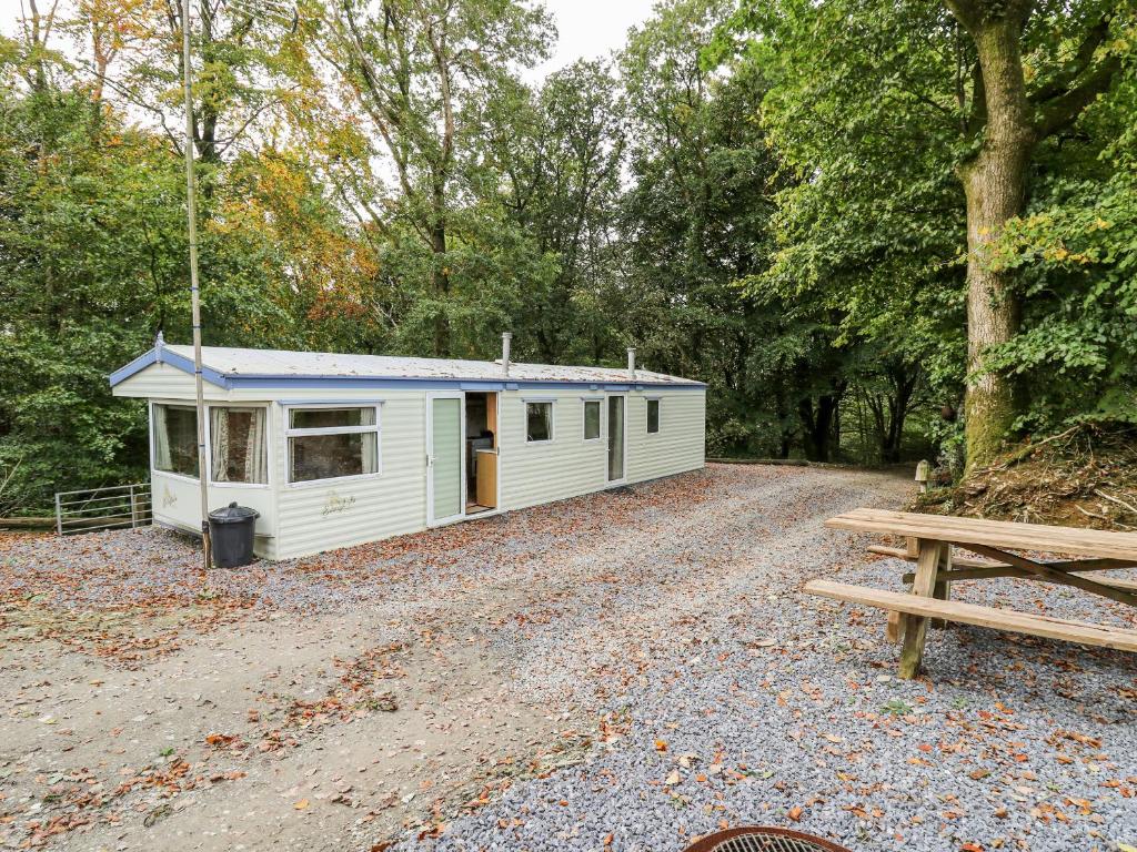 a small white cabin in the woods with a picnic table at Chill Out Holiday in Pencader