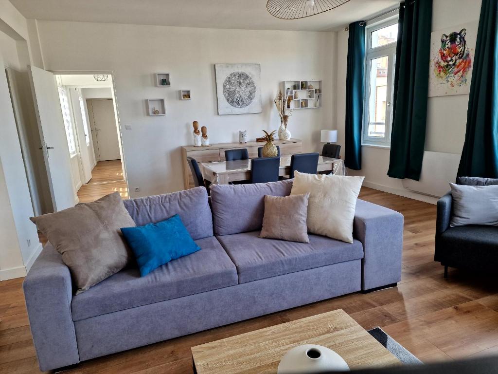ein Wohnzimmer mit einem blauen Sofa und einem Tisch in der Unterkunft Appartement Dunkerque in Dunkerque