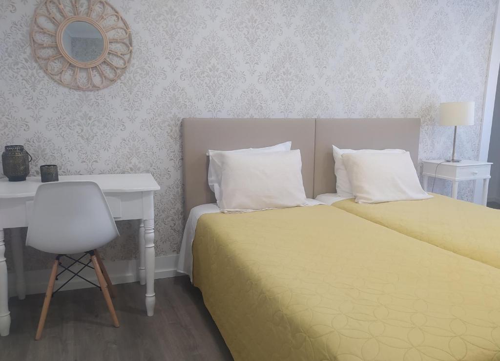 a bedroom with a bed and a desk and a mirror at Mondalva Guesthouse in São Pedro de Alva