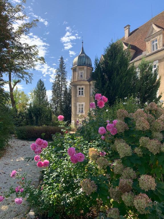 un edificio con una torre de reloj en medio de flores en Schloß Hürbel Rosengarten - Suite, en Gutenzell-Hürbel