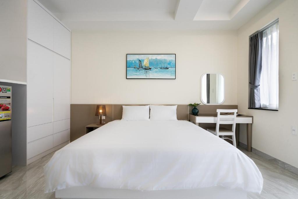 a white bedroom with a white bed and a desk at F-APARTMENT in Ho Chi Minh City