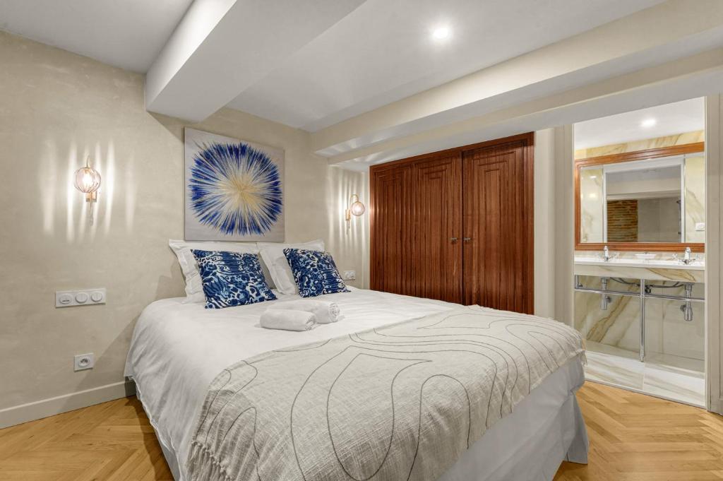 a bedroom with a large white bed with blue pillows at Les Relais du Capitole - Appartements d'hôtes in Toulouse