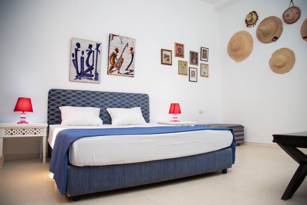 a bedroom with a blue bed with two lamps and pictures on the wall at La Grande Suite de Tozeur in Tozeur