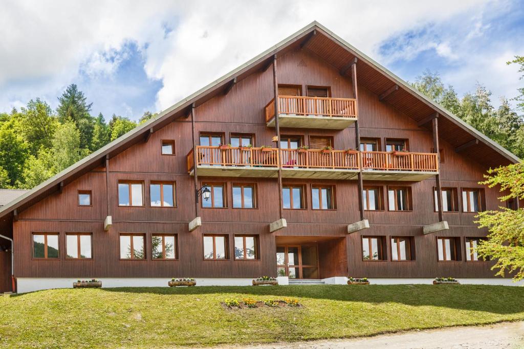 a large wooden building with a balcony at Auberge de jeunesse HI Valmeinier in Valmeinier
