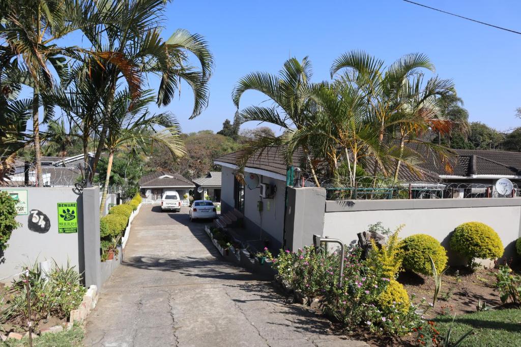 a white house with palm trees and a driveway at Enhle Bed and Breakfast in KwaDukuza