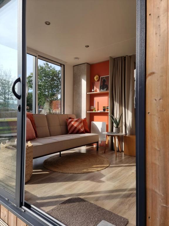 uma sala de estar com um sofá e uma mesa em Tiny house aan het Zuidlaardermeer - vlakbij Groningen em Kropswolde